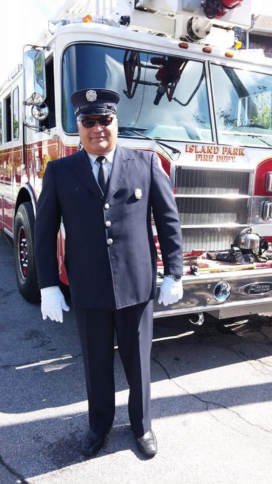 A man in a fire official suit stands in front of a fire truck