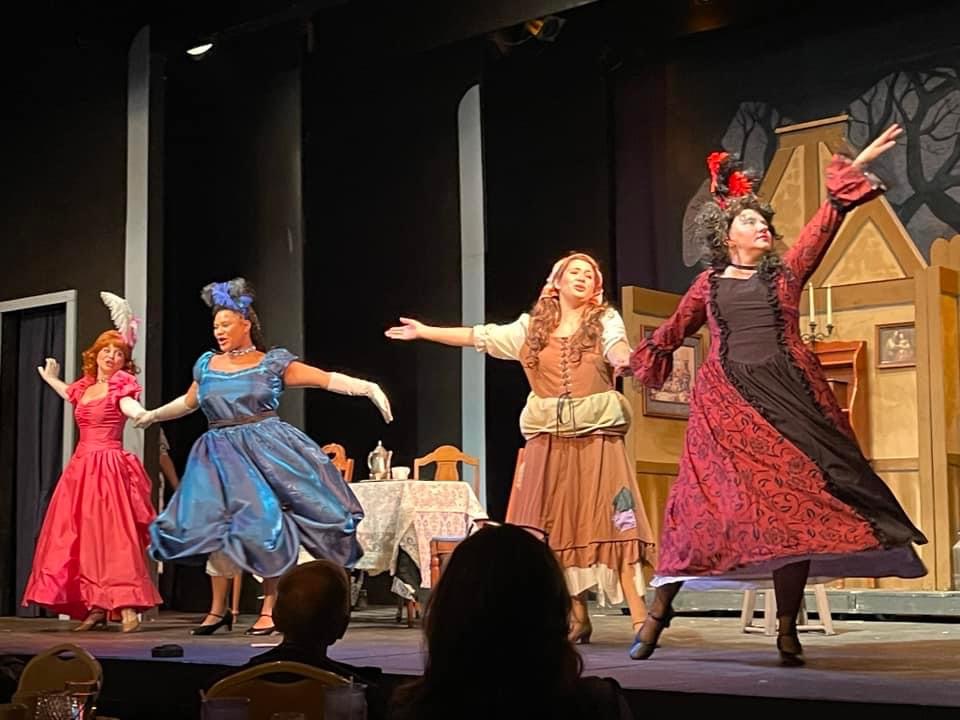 Four people in fancy dress costumes dance on a stage