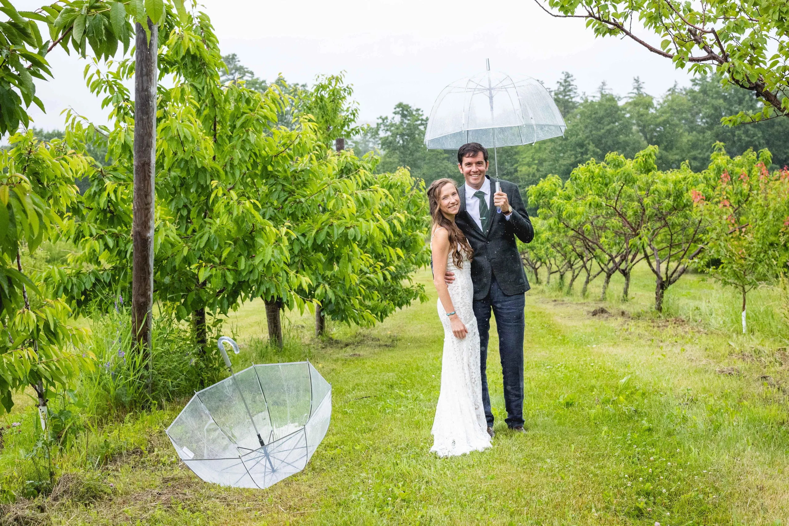 A wedding photo of a bride and groom outside under an umbrella