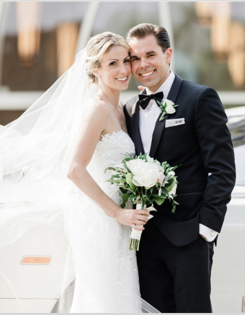 A newly married couple in wedding attire smiles for a wedding photo