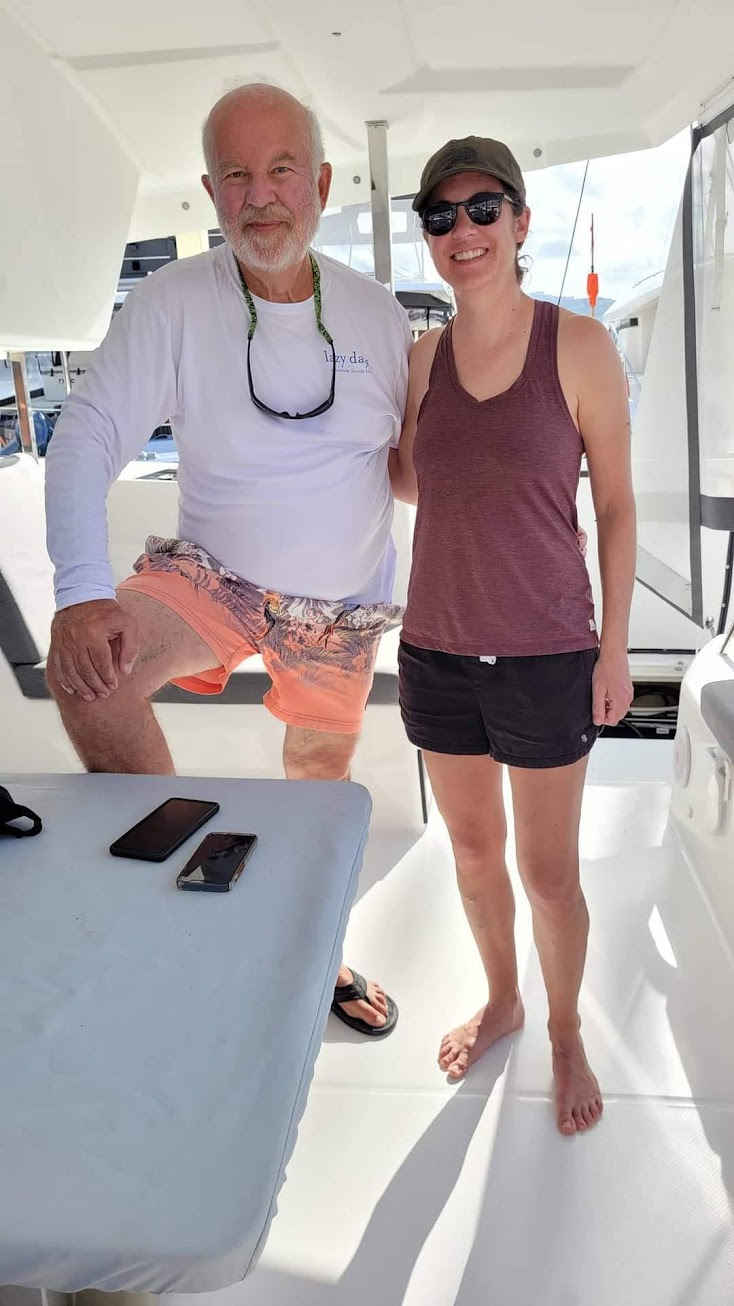 Two adults stand on a sailboat