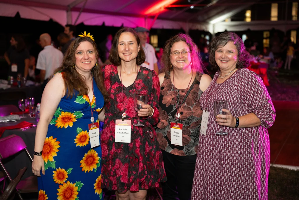 Four women smile for a photo under a tent