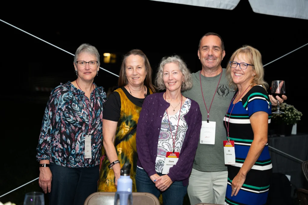 A group of five adults smiles for a photo