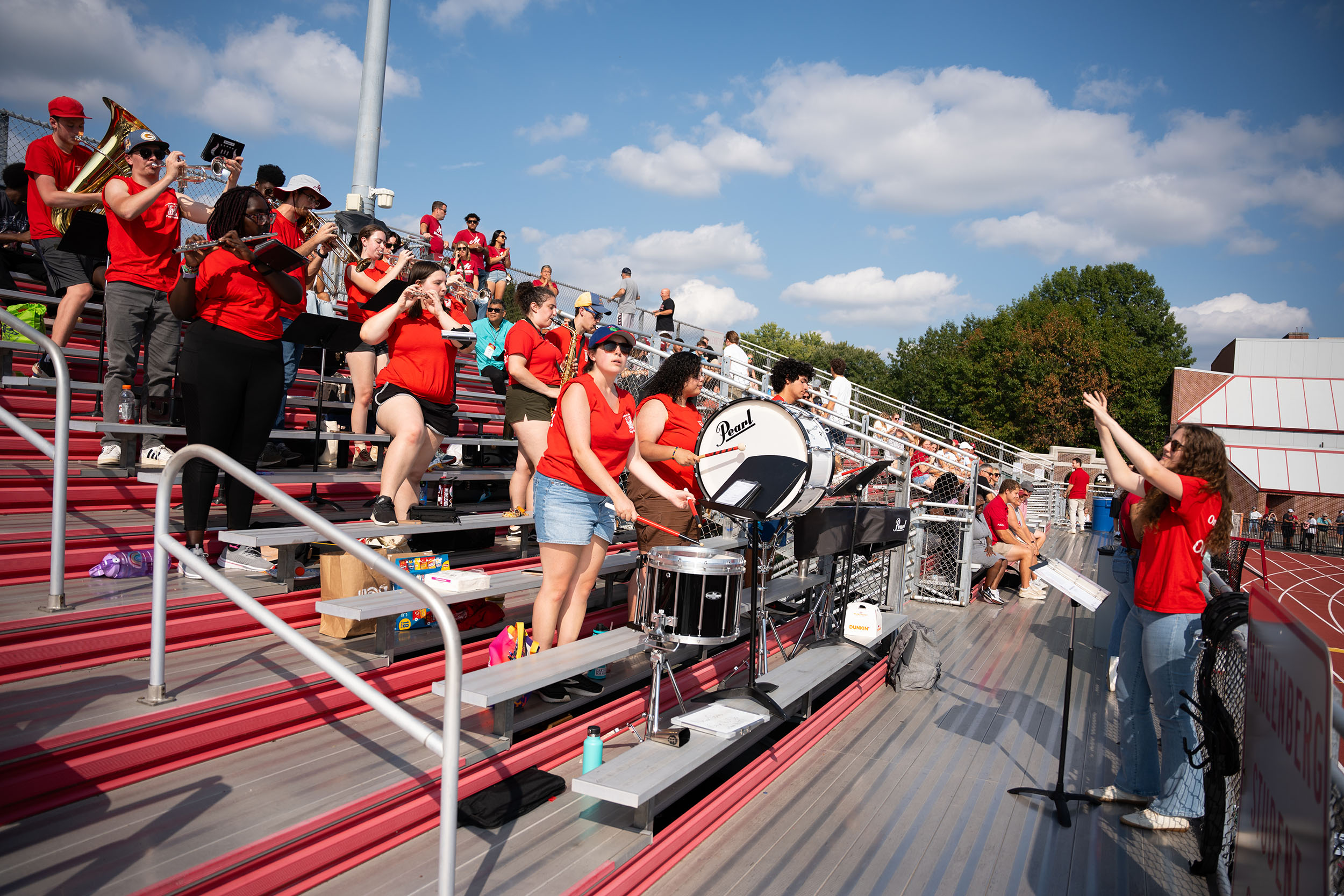 A band of college students plays in the stands of an outdoor stadium