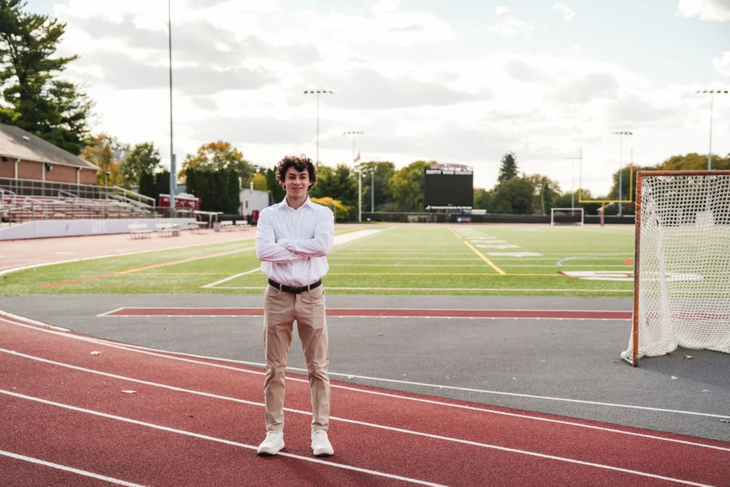 A college student stands in front of a track