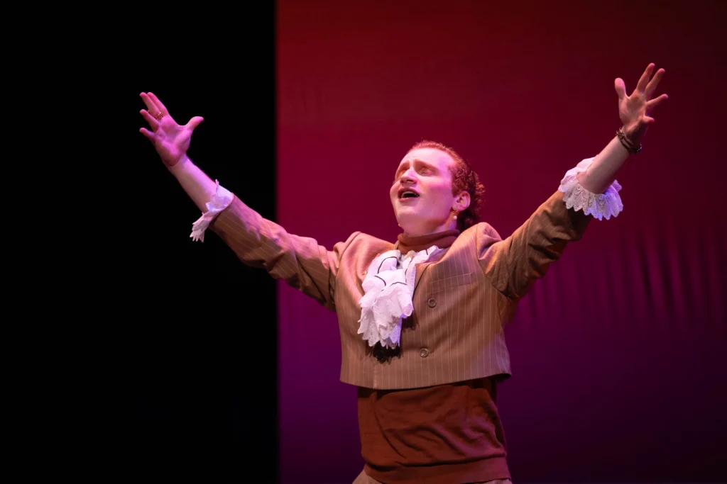 Samuel Roter with arms up in a gesture during a theatre production