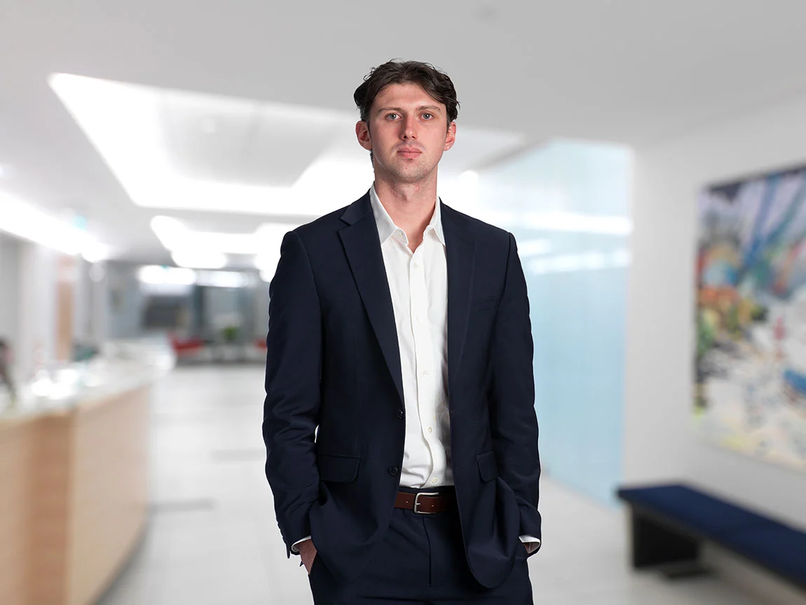 A headshot of a young man in a suit inside a law firm