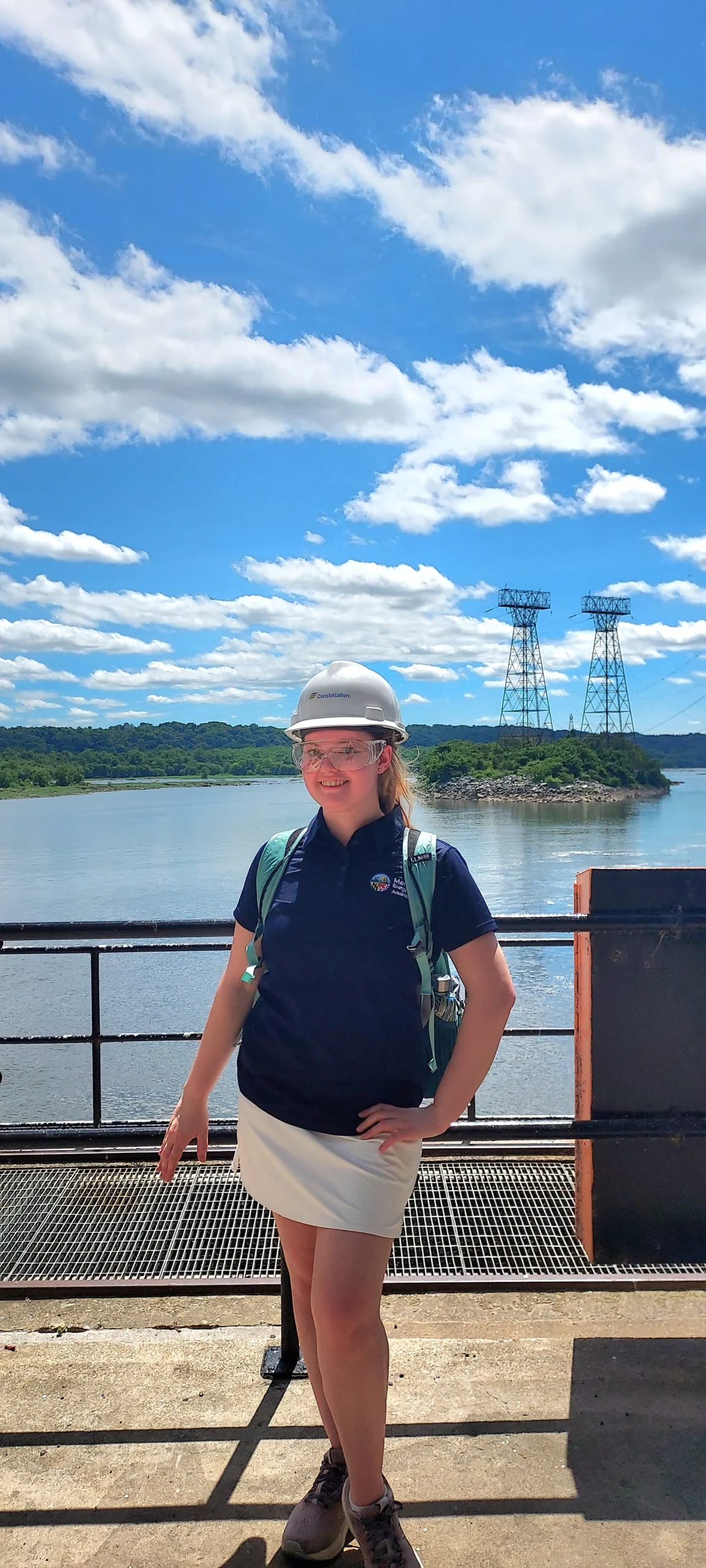 A young woman in a hard hat stands outside