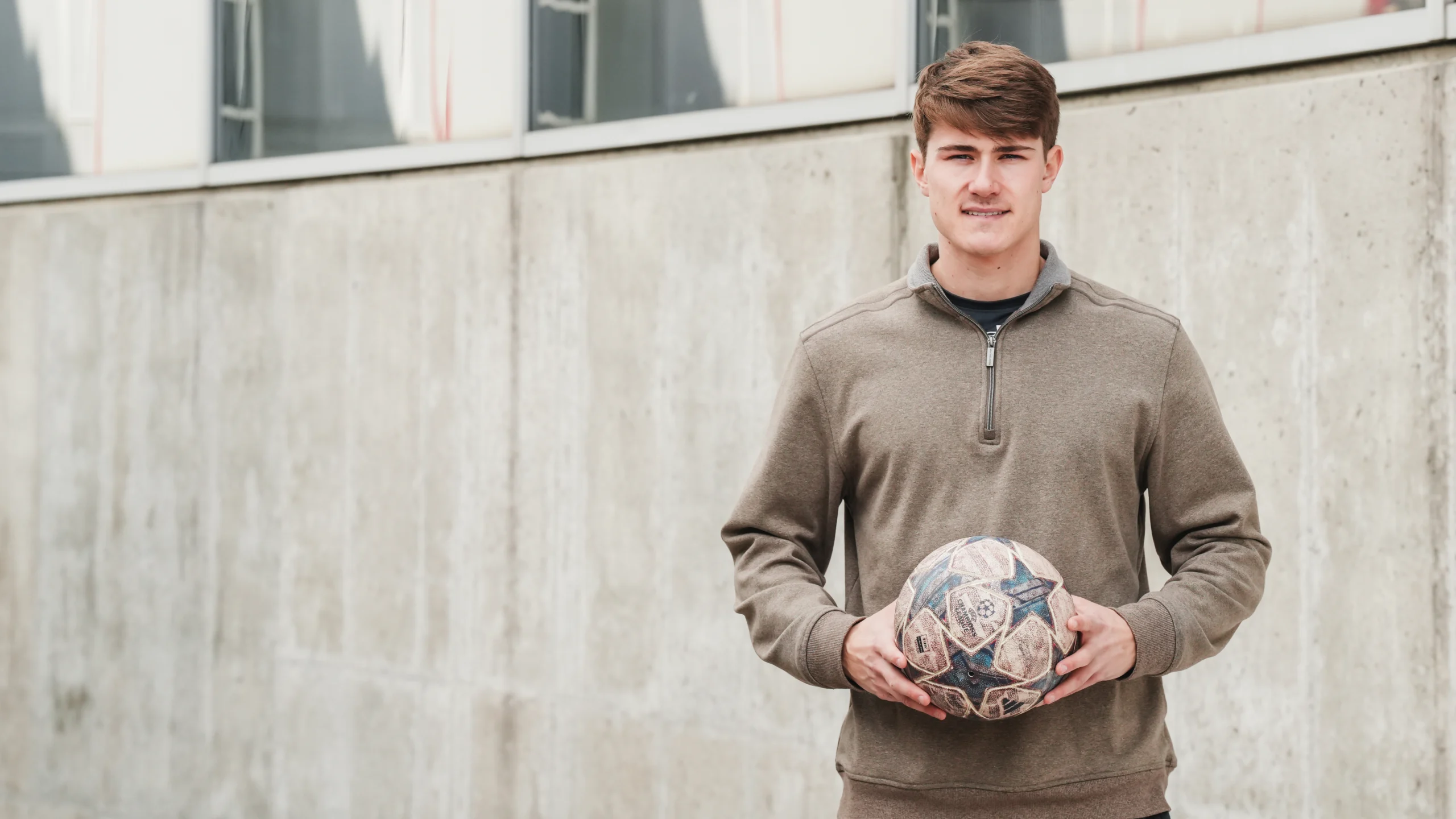 Evan Schlotterbeck looking at the camera smiling with a soccer ball in his hands