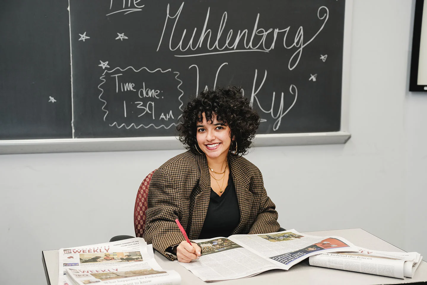 A college student in a houndstooth blazer in a student newspaper office