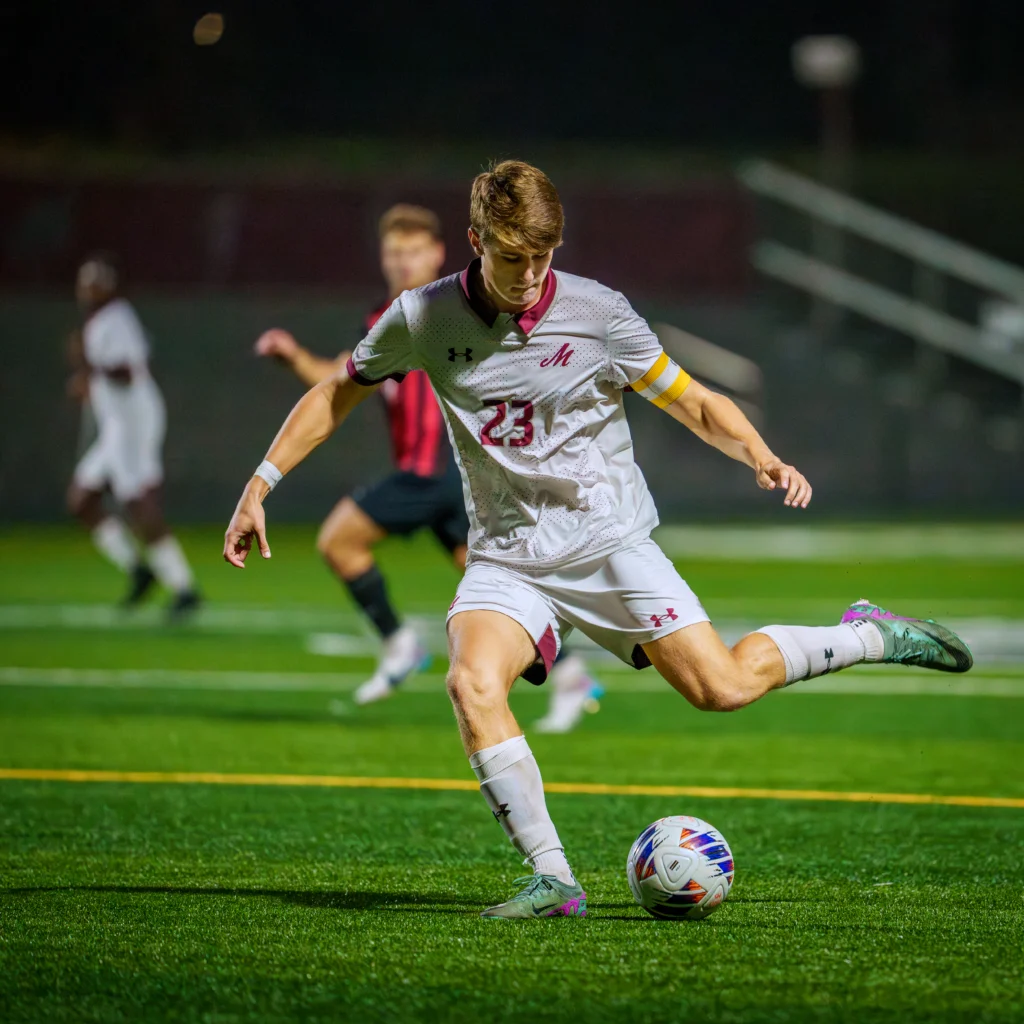 Evan Schlotterbeck in motion to take a kick at a soccer ball during a night game on a soccer field