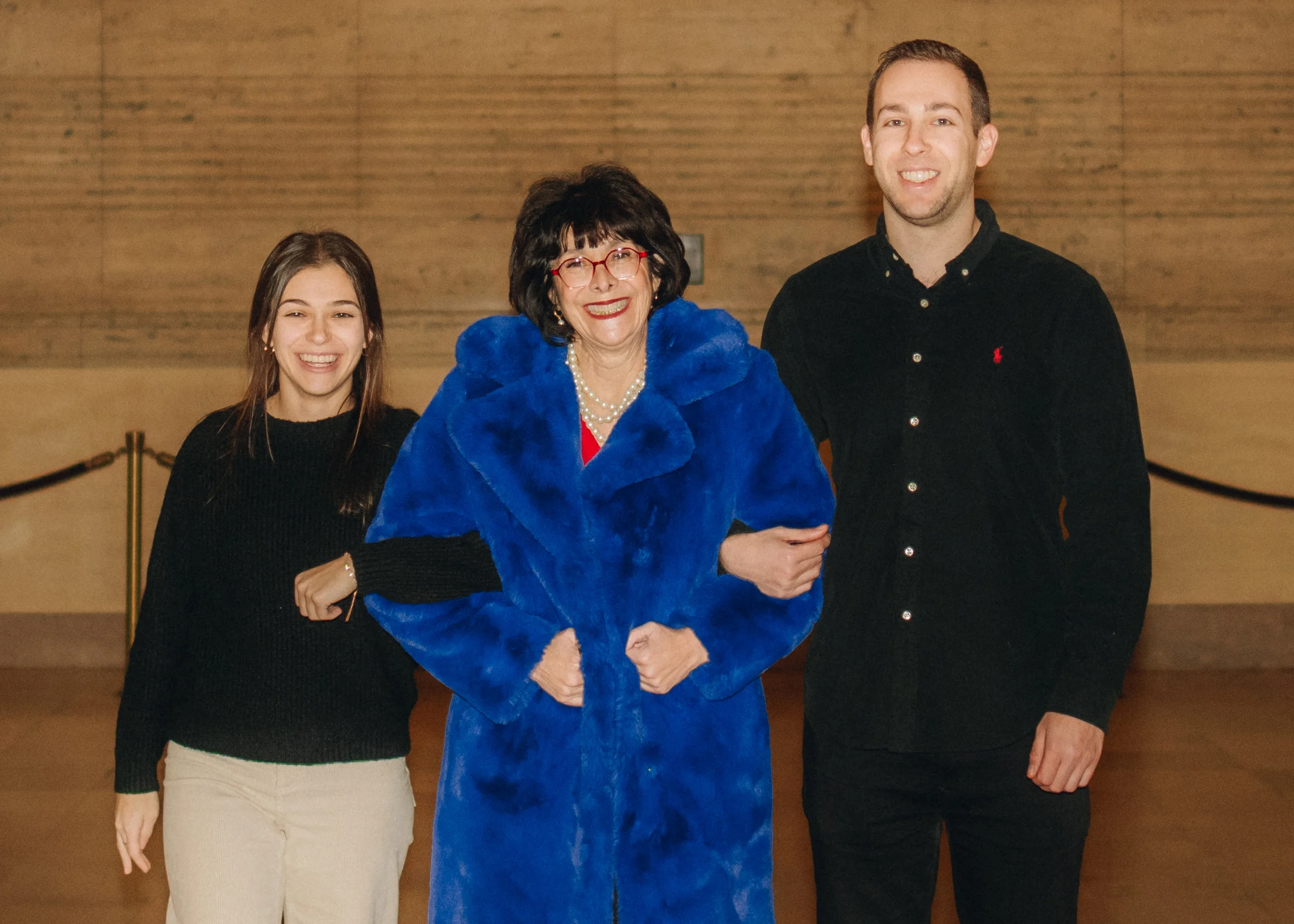 A photo of Emma Rosenthal, her mother, and brother with looped arms smiling at the camera