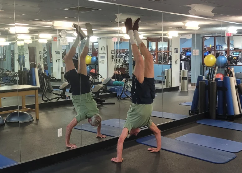 Photo of Paul Budline doing a handstand in front of a a wall of mirrors