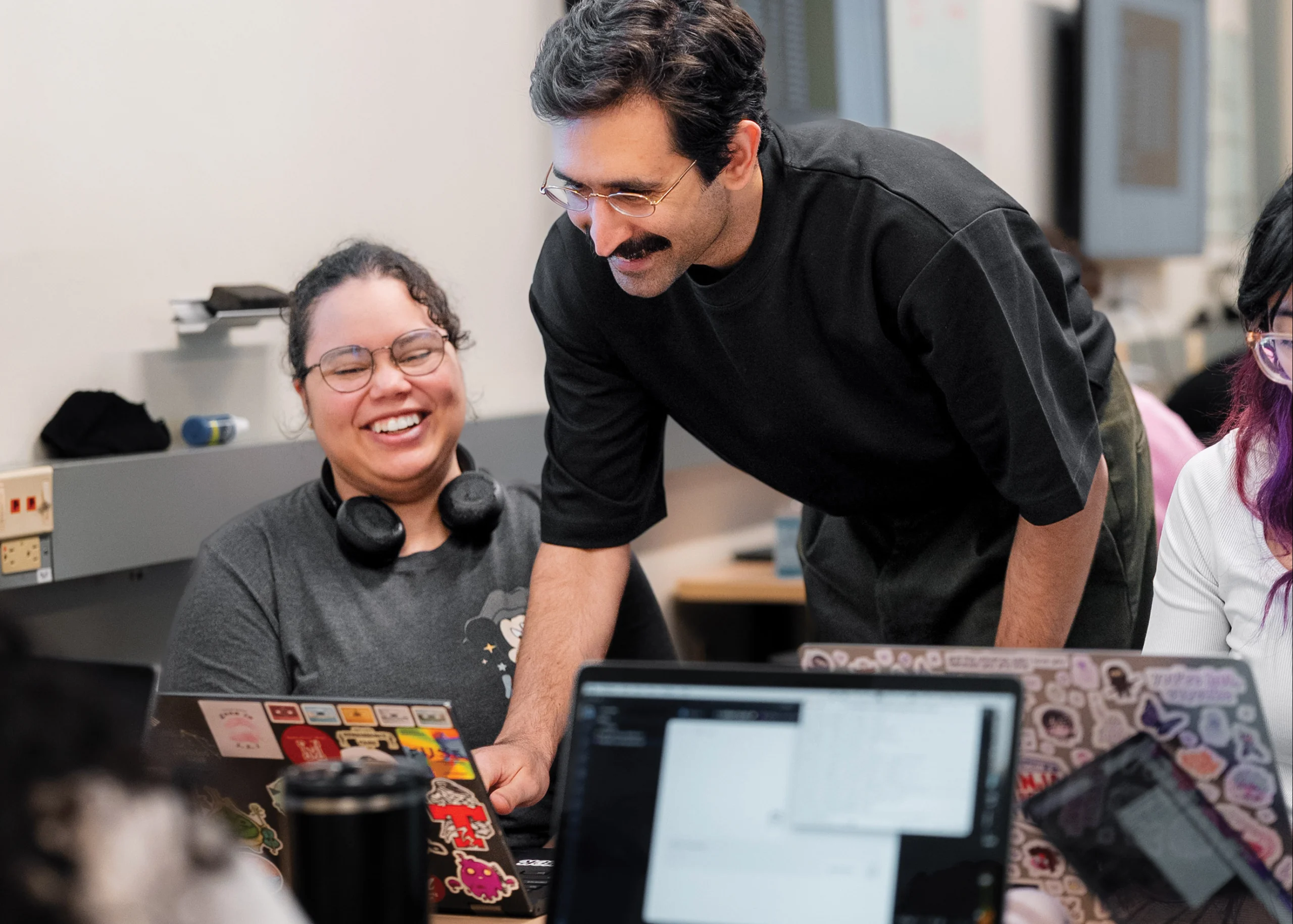 Photo of Hamed Yaghoobian working with a smiling student on their laptop