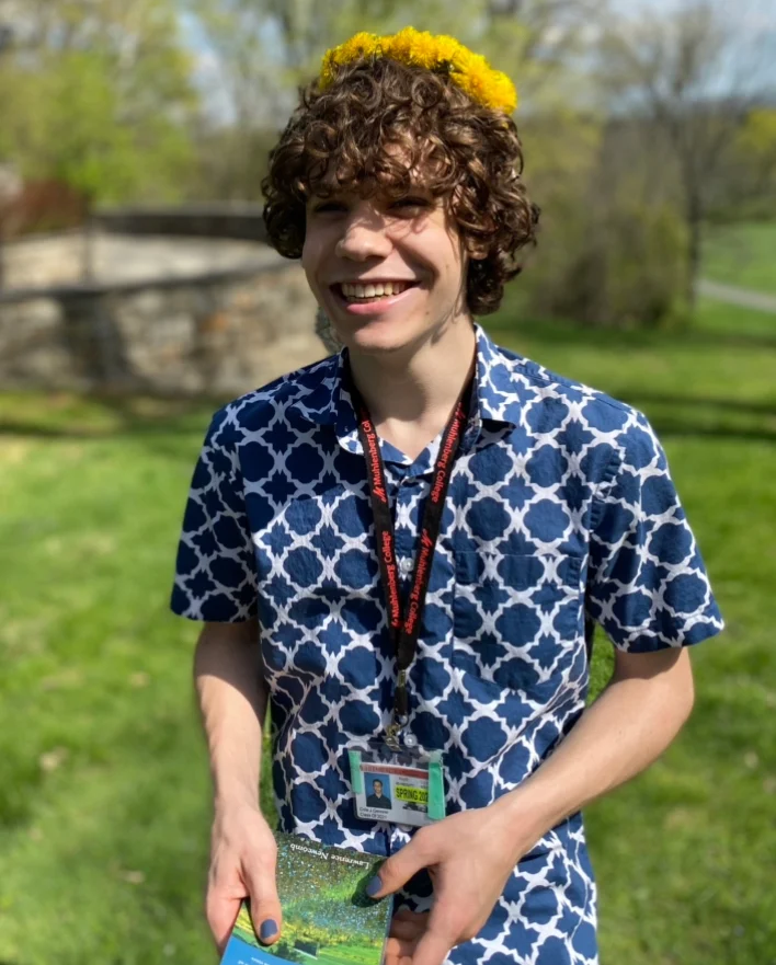 A Muhlenberg College student in a blue shirt with flowers in his hair